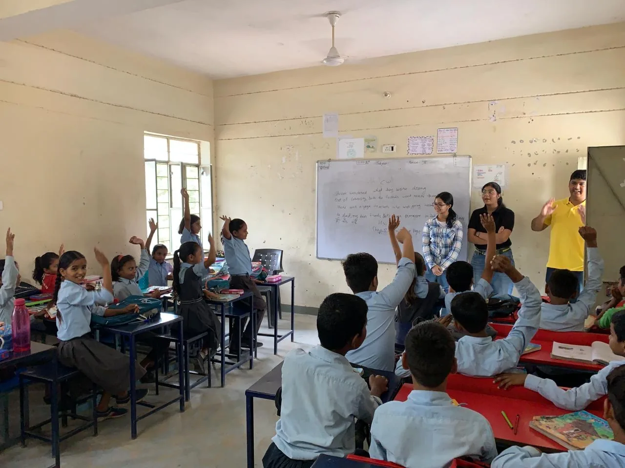 Volunteers addressing a classroom of students with raised hands